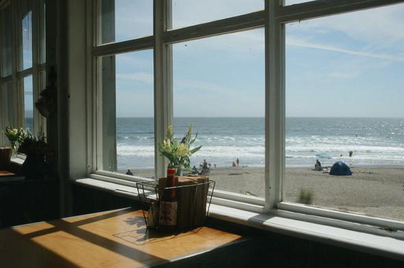 Blue skies, gentle sea and beach just beyond the shadows of a restaurant table