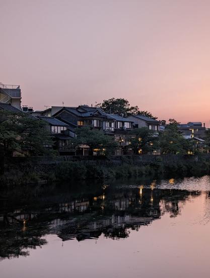 A traditional neighborhood by the river in Kanazawa. Traditional houses can be seen reflected in the calm river waters with the dusk light painting everything with a soft light.