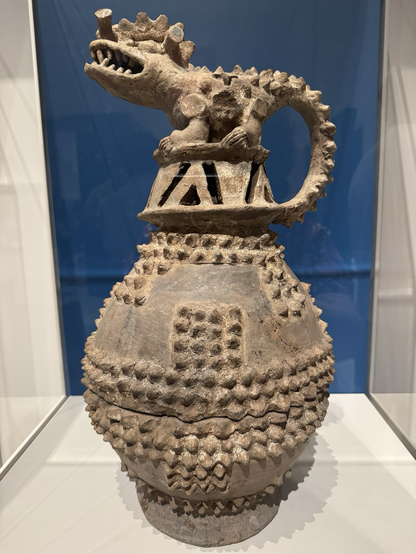 photo of the piece at museum “This incense burner is topped with the portrayal of a caiman or other member of the Crocodylidae family, one of the frequent animal spirit forms of Central American shamans. Its particularly aggressive stance may refer to the practitioner's battle against supernatural forces. Many such incense burners were found ritually broken on slopes of a principal volcano on the island of Ometepe in Lake Nicaragua, the incense burner lid with its smoke issuing from the top mimicking an active volcano. Among peoples from southern Nicaragua to Mesoamerica the earth was likened to the back of a crocodile floating in the primordial sea, its dorsal scutes being the volcanic north-south backbone that defines the continents of the Western Hemisphere. This incense burner, then, constitutes a profound ritual vessel pertaining to the transition from natural to supernatural realms & a symbolic model of the ancient Costa Rican world.” https://art.thewalters.org/object/2009.20.45/