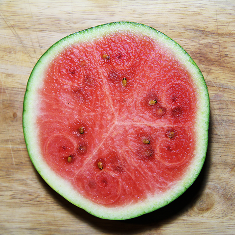A slice of watermelon with rind, cut out equatorially, showing segmentation and an interesting spiraling growth pattern.