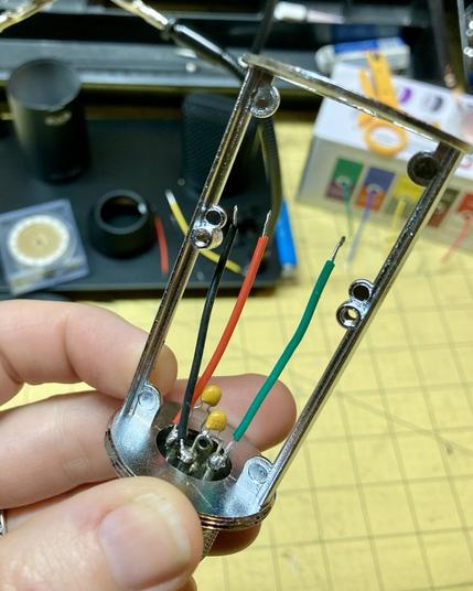 Close up photo of a microphone frame showing two capacitors and three wires soldered to the XLR pins.