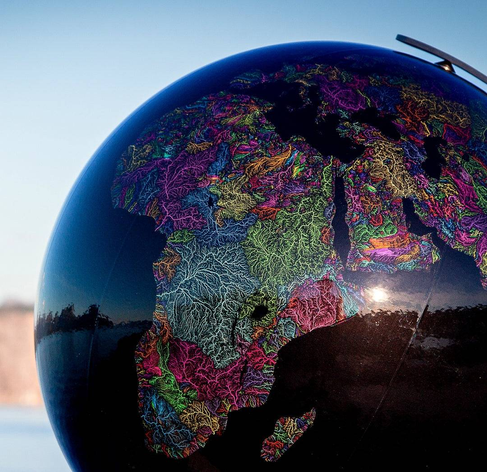 A globe of the Earth, but instead of a political or altitude map it's a colored map of watersheds with brightly-colored rivers making for the natural regions of the planet