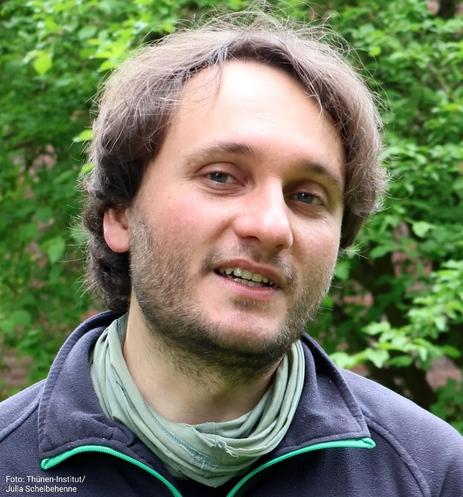 Porträt eines Mannes, der gerade etwas erzählt, vor Bäumen.