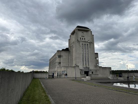 The exterior of the main building: a collossal concrete art-deco design against an ominous clouds in the background.