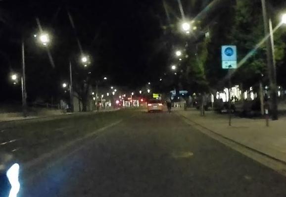 POV Radfahrer: Ein Autofahrer überholt eine Radfahrerin in einer Fahrradstraße mit Kraftverkehrsfreigabe mit ca. 50cm Abstand. Es ist Nacht und die Bildqualität schlecht.