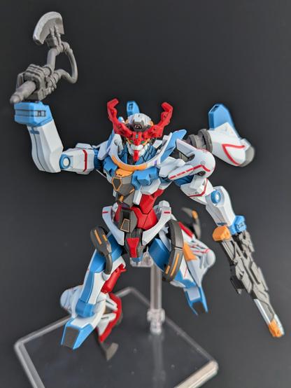 The HG GQuuuuuuX leaping toward the viewer brandishing its heat hawk. It is holding its rifle in its left hand pointed toward the ground. The blade of the heat hawk has been painted aluminum.