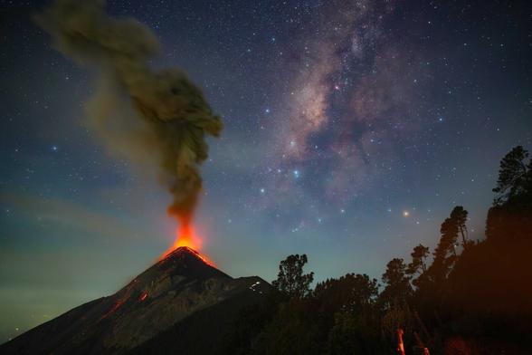 Photo of erupting volcano at night with Milky Way in background. By Sergio Montùfar, entitled "Cosmic Fire"