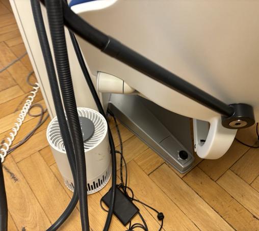 Ein Taotronics TT-AP001 Luftreiniger mit 12V PD Triggerkabel und 20k Powerbank neben  einem Stuhl in der Zahnarztpraxis.