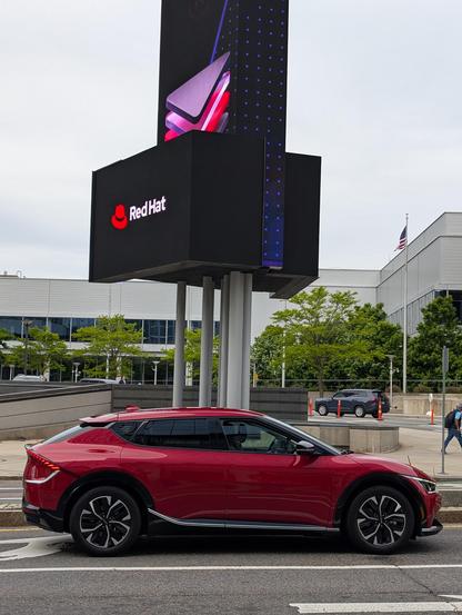 Red Kia EV6 in front of Red Hat sign