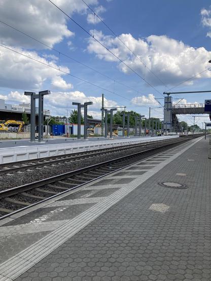 Zu sehen ist der Beueler Bahnhof in Richtung Koblenz. Zahlreiche Metallträger für eine Dachkonstruktion am gegenüberliegenden neu gebautem Bahnsteig sind aufgestellt. Der Himmel Strahl blau mit zunehmend weißen Wolken.