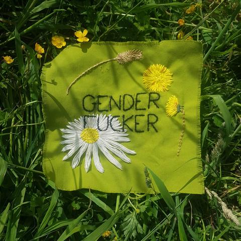 Photo de plus loin, on y voit mieux la paquerette et que le patch est posé sur de l'herbe et quelques petites fleurs jaunes.