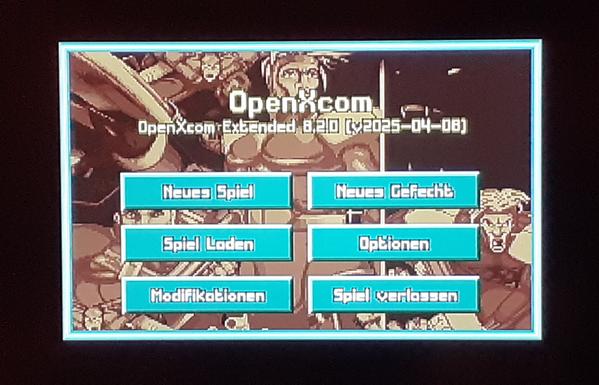 Das Startmenü von UFO/XCOM in der OpenXCOM Extended Version. Man sieht 6 türkis farbene Schaltflächen auf einem Spiele-Hintergrundbild wo man neue Spiele starten, laden oder Einstellungen vornehmen kann.