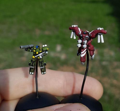 teeny tiny flying humanoid robots, kind of like gundams but not, one green with silver and yellow accents, one burgundy with white lines and silver bits.