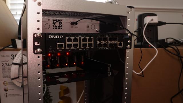 The QNAP QSW-M3216R-8S8T switch mounted in the second slot of the back of the minirack.  Above it is the Mikrotik switch (mounted in the front of the rack) and below it are the Raspberry Pis.