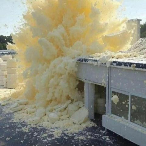 A photograph of a square concrete building with yellow solid debris all around it