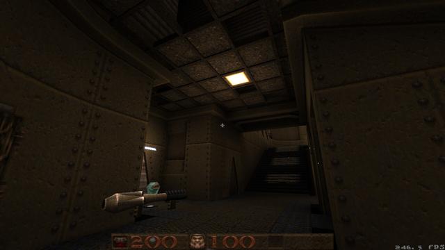 A screenshot of the video game Quake taken from the position between red armor stairs and megahealth where the rocket launcher spawns, looking up the RA stairs. Visible is a goofy and unfinished drop ceiling with an inset light.