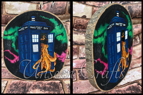 Two photos of Oval wood slice with burned design showing an orange octopus coming out of a blue police call box. The background is black with streaks of vibrant green and pink. Second photo shows side view.