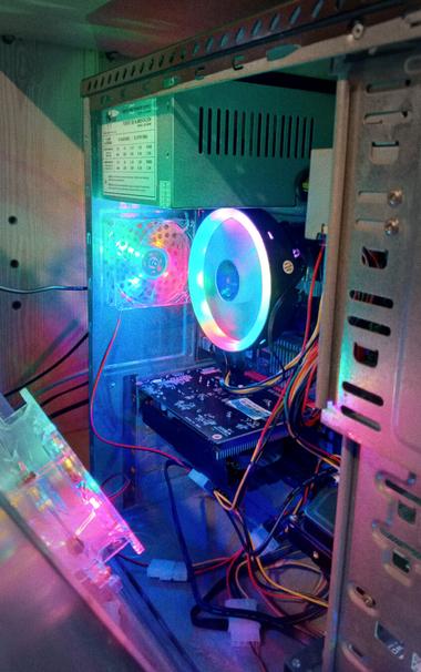 A photo of the insides of an open PC. The PC is on and RGB fan coolers are whirring.