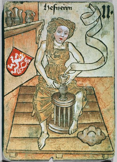 A medieval image of a female potter working with bare feet on an elegant pot in front of her on the kickwheel. There's a pile of clay in the foreground, some jugs on a shelf in the background, a red shield with a white lion to the left and the name "hefneryn" written above her head.