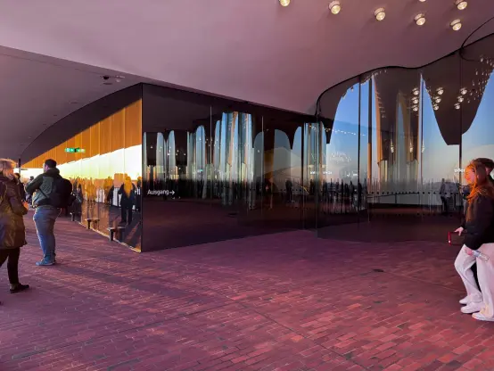 On the viewing terrace at the Elphilharmonie, the sunset is tinting the exit area in orange and pink.