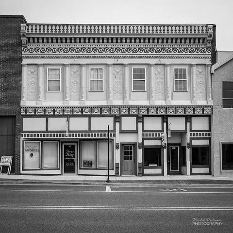moldings at the roofline and between floors.  There are two businesses in the bottom level and a door leading to second floor apartments or offices.