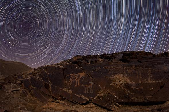 2012 July 12

Teimareh Petroglyphs and Star Trails
 * Image Credit & Copyright: Babak Tafreshi (TWAN)

Explanation: 
Engraved in rock, these ancient petroglyphs are abundant in the Teimareh valley, located in the Zagros Mountains of central Iran. They likely tell a tale of hunters and animals found in the middle eastern valley 6,000 years ago or more, etched by artists in a prehistoric age. In the night sky above are star trails etched by the rotation of planet Earth during the long composite exposure made with a modern digital camera. On the left, the center of the star trail arcs is the North Celestial Pole (NCP), the extension of Earth's axis into space. Polaris, the North Star, leaves the bright, short, stubby trail closest to the NCP. But when these petroglyphs were carved, Polaris would have made a long arc through the night. Since the Earth's rotation axis precesses like a wobbling top, 6,000 years ago the NCP was near the border of the constellations Draco and Ursa Major, some 30 degrees from its current location in planet Earth's sky. 

Authors & editors: Robert Nemiroff (MTU) & Jerry Bonnell (UMCP)
NASA Official: Phillip Newman Specific rights apply.
NASA Web Privacy Policy and Important Notices
A service of: ASD at NASA / GSFC
& Michigan Tech. U.