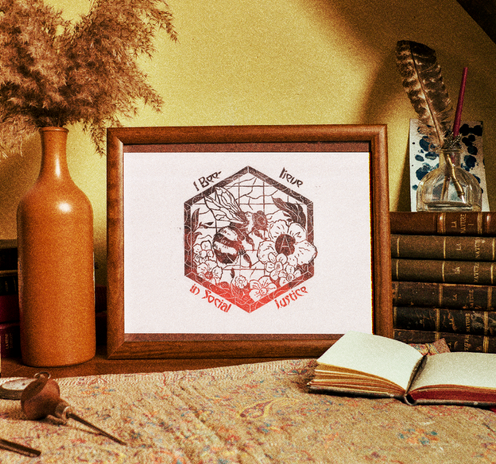 Linocut in red and black with a bumblebee gathering anarchist flowers. The linocut is set in a frame surrounded by old books, small objects and decorations with a warm, vintage feel.