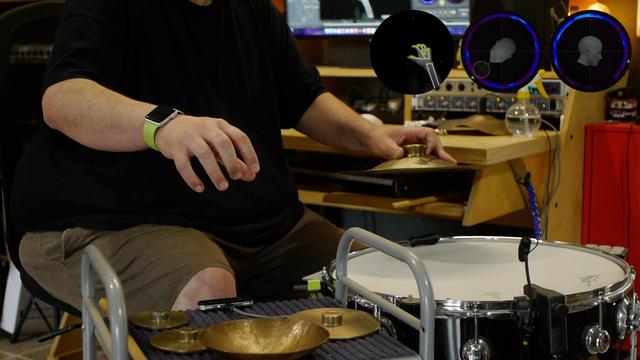 Hands hovering over a drum and motion sensor controller.