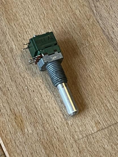 Drehpotentiometer mit grünem Gehäuse und metallener Front und Achse. Zu sehen sind die Anschlüsse und die Beschriftung TY (TV) 104B
