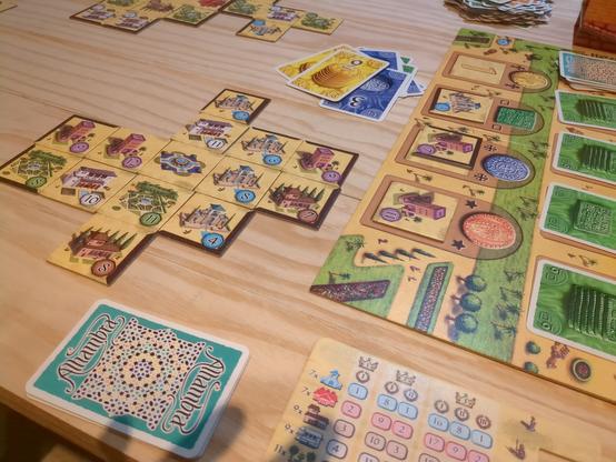 Spielplättchen und -karten auf einem Holztisch.