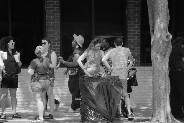 A group of people congregating on a side street, a child staring back in my direction but not at me