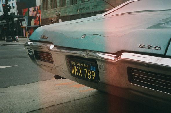 A 1968 Pontiac GTO is parked across the street from the Terra Cotta facade of the I Magnin Building Downtown Oakland.