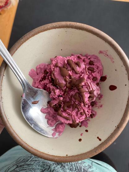 bright pink icecream in a bowl with chocolate drips on top