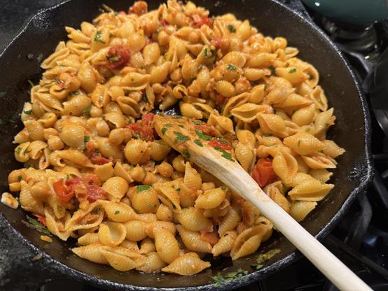 Cast iron pot with pasta dish and wooden spoon.