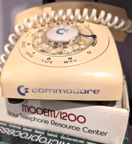 Canadian Commodore 64 rotary phone, a bit discolored and faded with age, sitting on a 1200 baud Modem box that contains a modem for a Commodore 64