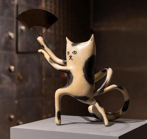 a sculpture of a cartoonish cat waving a fan