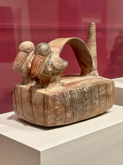 photo of the object on display at museum “The Peruvian Pelican, one of the largest seabirds of the region, is shown in a life-like manner on the top of the vessel. By contrast, the base is covered with abstract spiraling motifs that may evoke water and land, both of which provided a home for the pelican. Using a simple palette of red, white, and black, the potter was able to create a sense of animation, which would have been heightened when the whistle was blown, perhaps imitating the call of the pelican.” info via https://art.thewalters.org/object/48.2826/