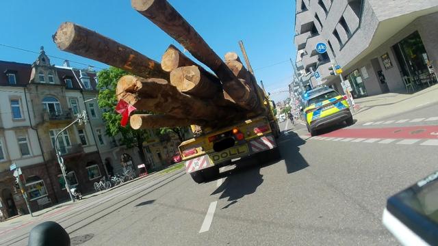 Ein Polizeifahrzeug parkt mit gesetztem Blaulicht nach einer Einmündung in einer Rechtskurve auf Radfahrstreifen und Fußgängerüberweg.