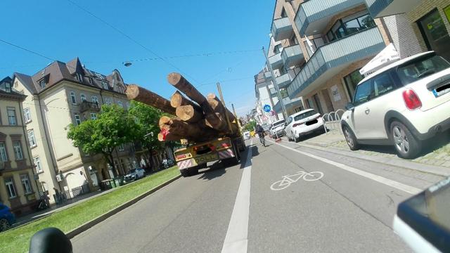 Ein Holztransport überholt einen Radfahrer unter Unterschreiten des Mindestabstands. Auch im Bild: Radweg Ende