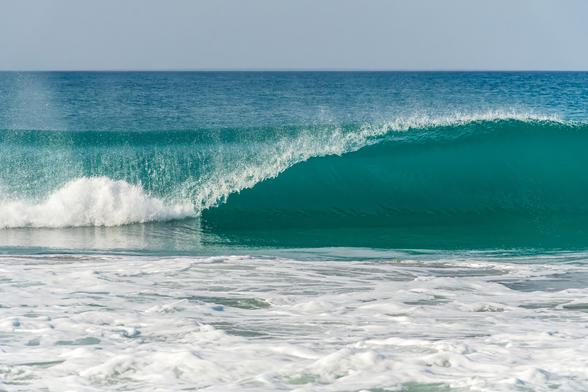 Das Bild zeigt eine atemberaubende, türkisfarbene Brandungswelle, die an einen Strand rollt.


Das Bild zeigt eine einzelne, große Ozeanwelle, die sich in einer sanften Kurve über die Wasseroberfläche bricht.  Die Farbe des Wassers ist ein leuchtendes Türkis, das in den Tiefen zu einem dunkleren Blau übergeht.  Der obere Teil der Welle ist weiß schäumend, während der Hauptteil der Welle ein kräftiges Türkist zeigt. Der Vordergrund wird von aufgewühltem, weißem Schaum und Gischt dominiert, der sich auf dem flacheren Wasser des Strandes ausbreitet. Der Hintergrund zeigt einen ruhigen, wolkenlosen Himmel in einem blassen Blaugrau.  Es sind keine Personen, Tiere oder anderen Objekte außer Meer und Himmel sichtbar. Die allgemeine Stimmung des Bildes ist ruhig und friedlich, zugleich aber auch kraftvoll und dynamisch, dank der imposanten Welle.  Es vermittelt ein Gefühl von Freiheit und der unbändigen Kraft der Natur.