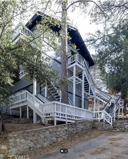 The outside of a 4 story house which has stairs going around the side and up and across the building in a ton of different directions and it's hard to tell where they actually wrap around to go up.