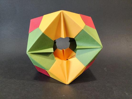 Photo of the cuboctahedron. Made with yellow, dark green and dark red pieces of paper.