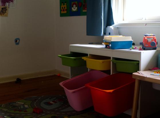 An abandoned child's bedroom, with toy drawers pulled out, but the space where the bed is has been left empty