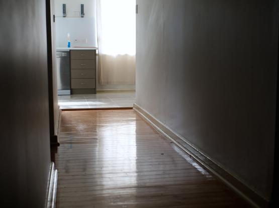 An empty hallway, with the light reflected on wooden floorboards