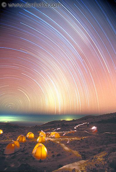 2004 September 11

The Star Trails of Kilimanjaro
 * Credit & Copyright: Dan Heller

Explanation: 
The night had no moon, but the stars were out. And camped at 16,000 feet on Mt. Kilimanjaro, photographer Dan Heller recorded this marvelous 3 1/2 hour long exposure. Here the landscape is lit mostly by the stars. Flashlights give the tents an erie internal radiance while the greenish glow from the distant city lights of Moshi, Tanzania filter through the clouds below. The view from this famous equatorial African mountain is toward the south, putting the South Celestial Pole close to the horizon on the far left, near the center of the graceful concentric star trail arcs. In the thin air and clear dark skies, even the ghostly Milky Way left a faint triangular glow as it swept across the middle of the dreamlike scene. 

Authors & editors: Robert Nemiroff (MTU) & Jerry Bonnell (USRA)
NASA Web Site Statements, Warnings, and Disclaimers
NASA Official: Phil Newman Specific rights apply.
A service of: ASD at NASA / GSFC
& Michigan Tech. U.