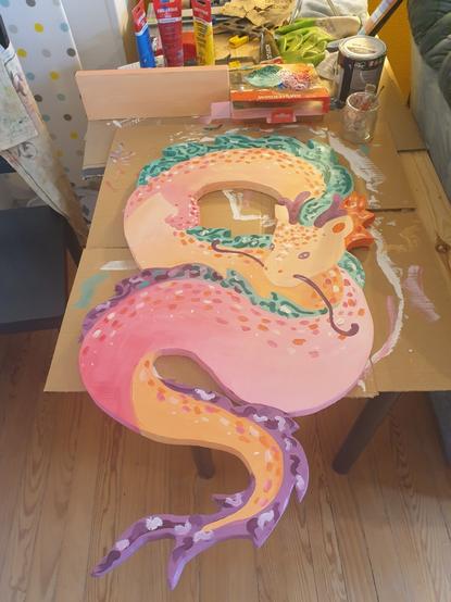 C'est mon étagère dragon, rose-orangé avrc des cheveux vert-violacés.
Derrière on voit ma peinture (toujours les quatre même tubes d'acrylique depuis cinq ans, je peins pas tant : couleurs primaires + blanc, et le noir dont je me suis pas servit) et mes pinceaux