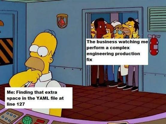 A group of people peering through a doorway is labeled, "The business watching me perform a complex engineering production fix." In the foreground, Homer Simpson stands at a control panel with his hand on his chin in a thinking pose, labeled, "Me: Finding that extra space in the YAML file at line 127."