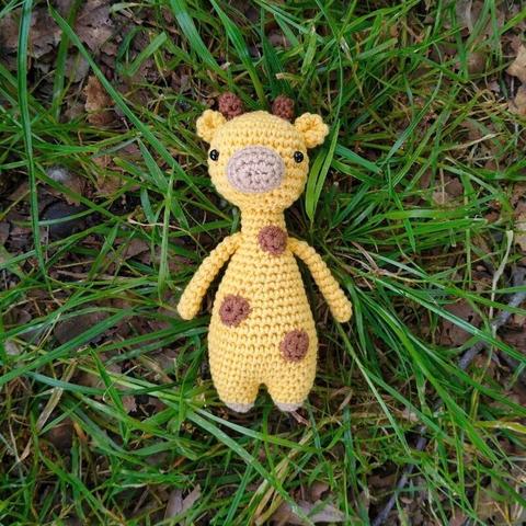 A picture of a crocheted amigurumi giraffe in grass.
