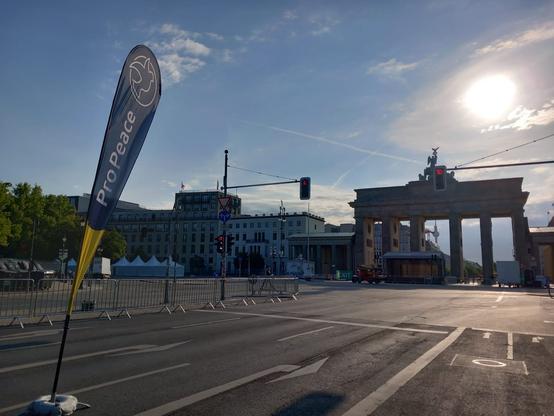 Brandenburger Tor in der Morgensonne, im Vordergrund eine Pro-Peace-Beachflag