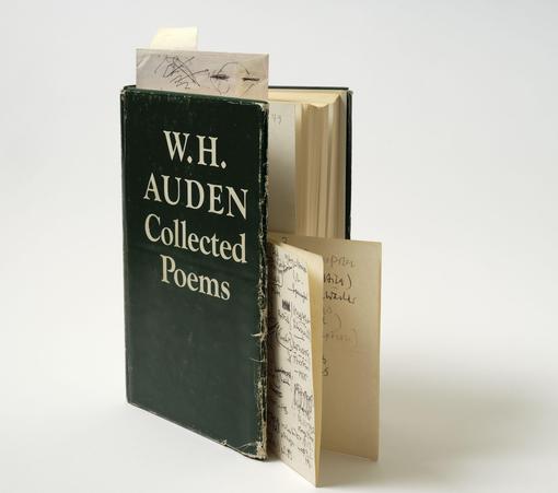 Vor einem weißen Hintergrund sieht man ein aufgestelltes, altaussehendes Buch mit der weißen Schrift "W.H. Auden, Collected Poems" auf dunklem Buchcover. Einige Zettel zeigen aus dem Buch heraus. Das Buch ist aus dem Heiner-Müller-Archiv.